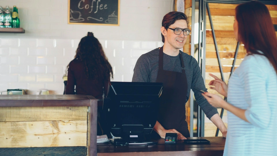 Cashier speaking with a customer across a cafe counter