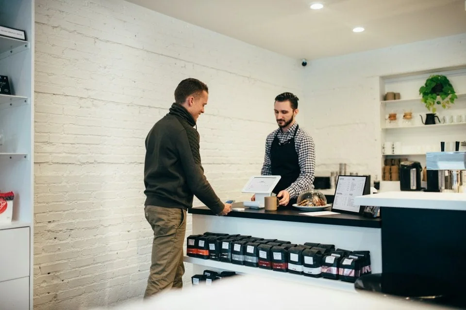 Customer paying at a café counter with a tablet point-of-sale terminal