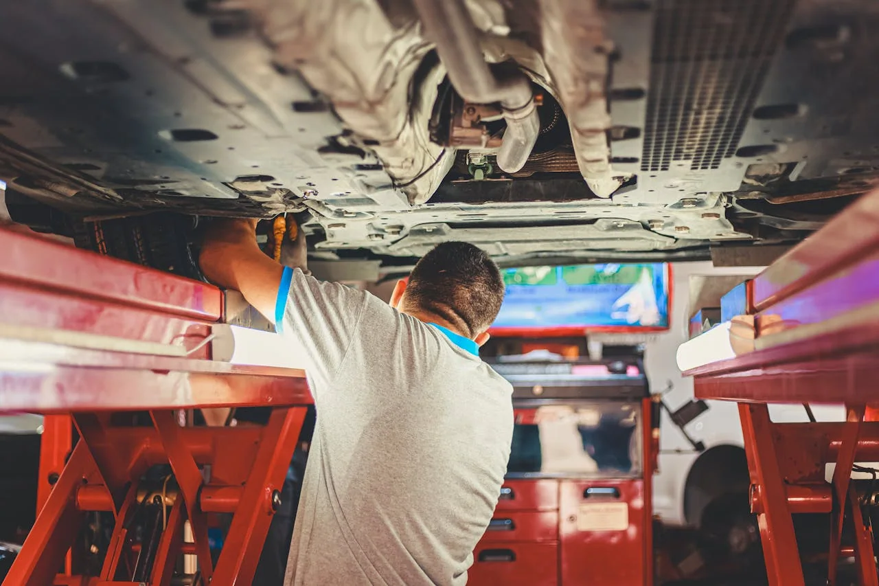 Mechanic working underneath a car on a vehicle lift