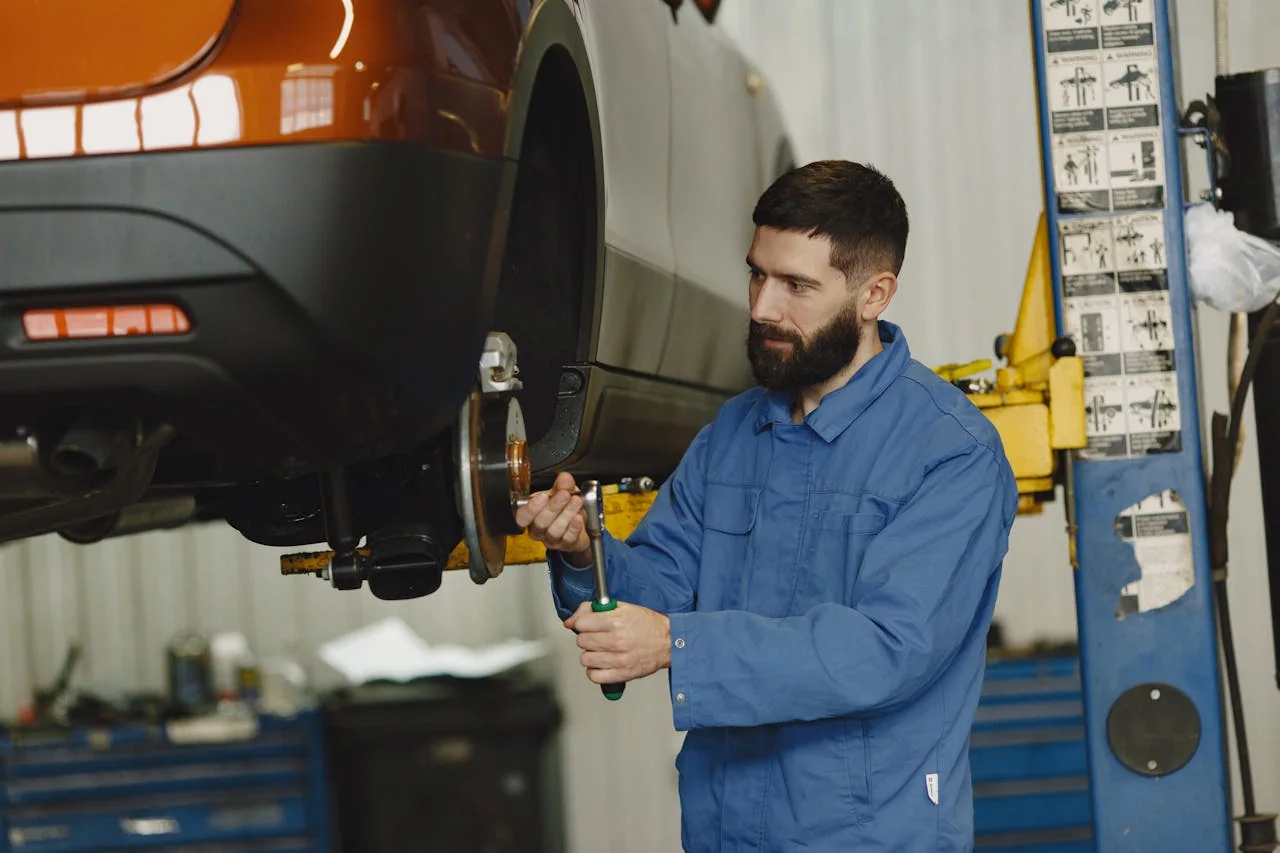 Mechanic servicing wheel brakes on a vehicle lift