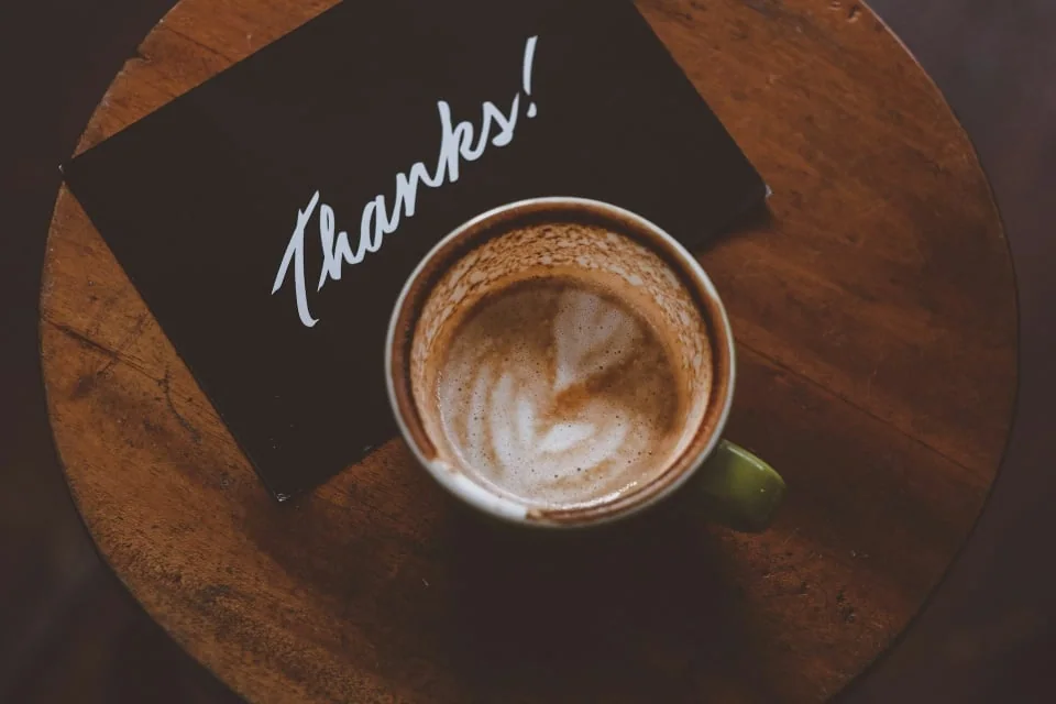 Coffee and a thank-you card on a wooden table