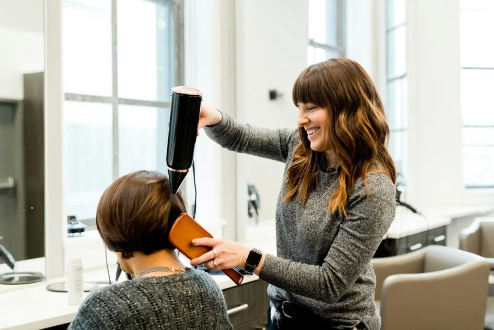 Hairdresser blow-drying a customer's hair in a salon